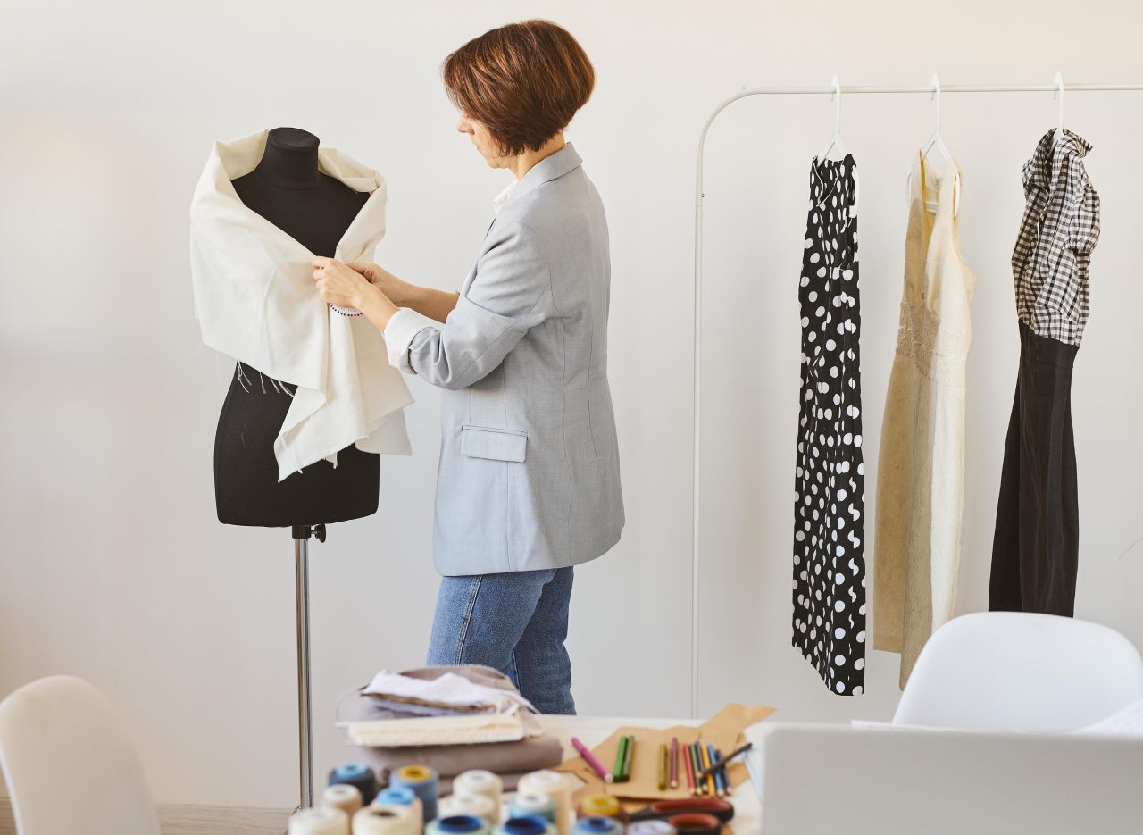 Side view of female fashion designer in atelier with dress form